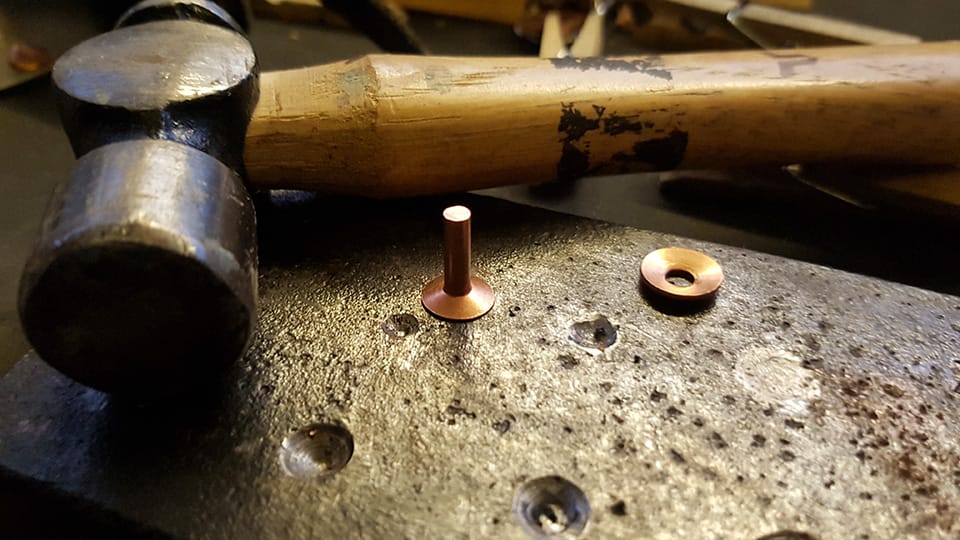 I drilled shallow holes in my makeshift block of mild steel to help with the rivet process.