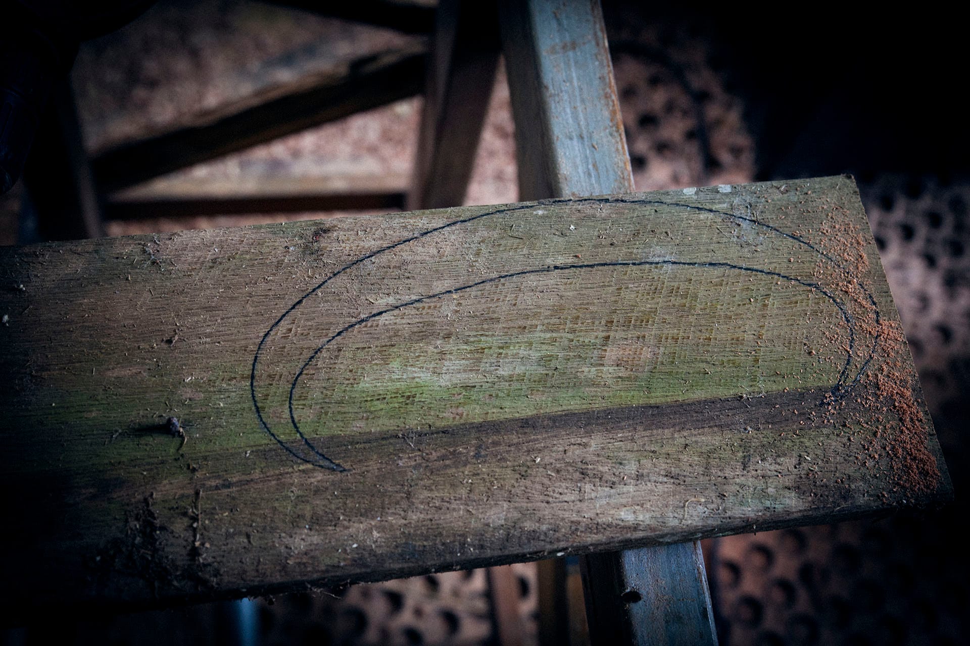 Marking out the guard shape on scrap wood from the firewood pile